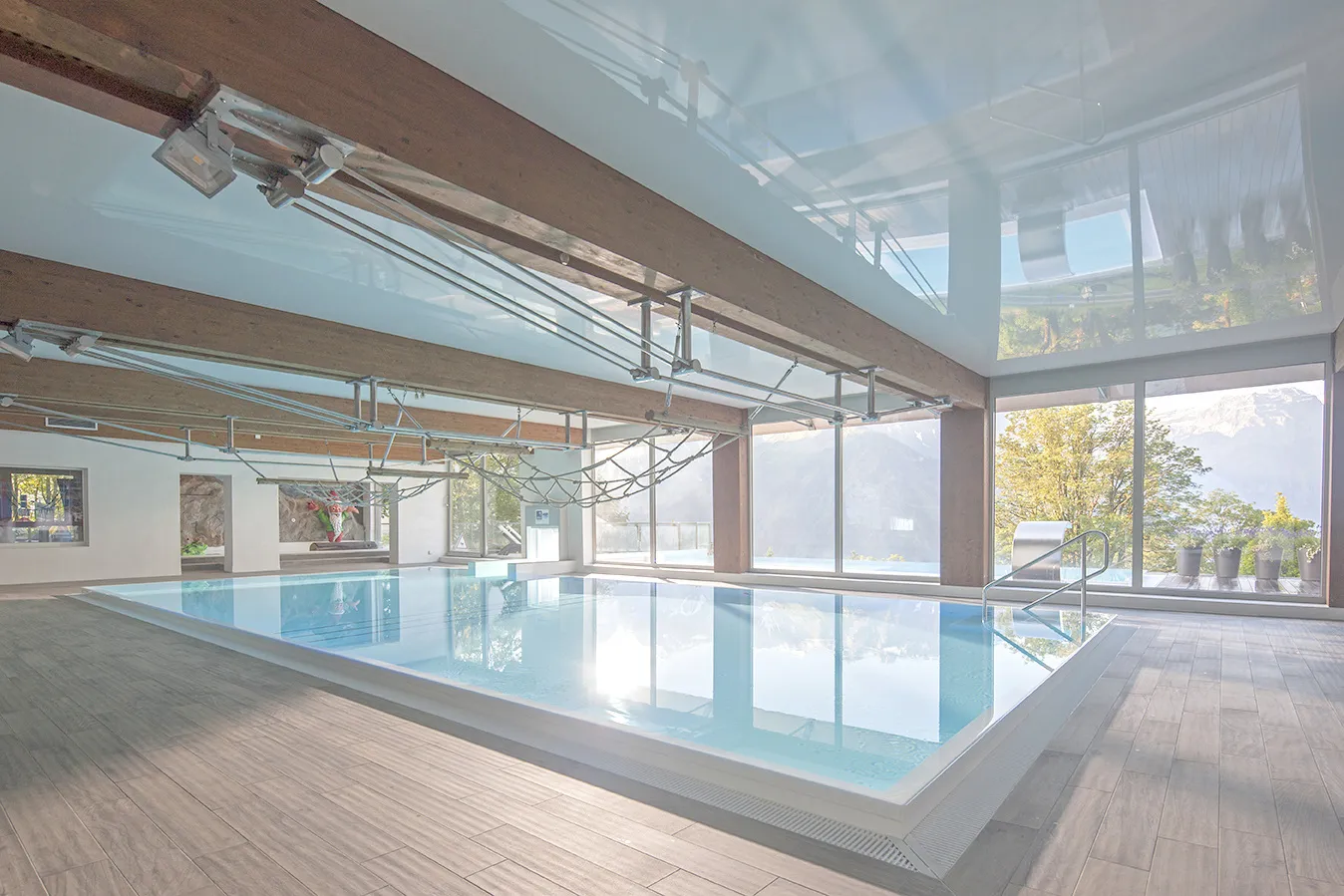 Bild zeigt eine Schwimmhalle mit großem Schwimmbecken, dass mit einem Außenbecken verbunden ist.